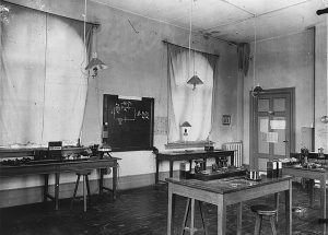 Interiør fra Den tekniske skole i Munkegaten 1. Bildet viser et klassserom med benker, bord, en tavle, undervisningsmateriell. Yrkesskole. 1898 - 1910. Foto: Erik Olsen/NTNU UB Lisens: CC BY-SA 4.0 ID: O-I-1968_01